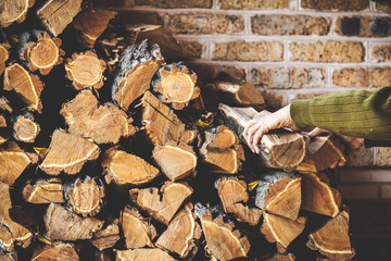 Man hands take log out of folded pile firewood