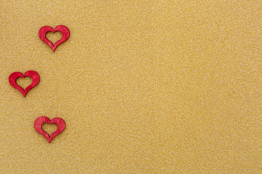 drei rote Herzen auf goldenem Hintergrund