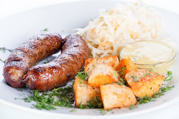 Roast meat sausages with potatoes and cabbage on a white backgro