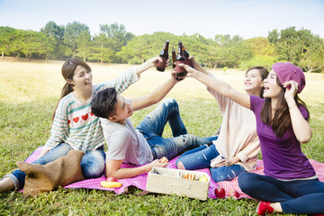 happy young friends enjoying picnic and drinking beer