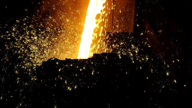 molten metal poured from ladle into mold at steel plant