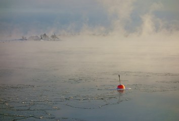 Bright red buoy floating alone in the freezing Baltic Sea in Helsinki, Finland just hours before complete freeze over of the sea on an extremely cold January morning (-20C) on 6 January 2016. 