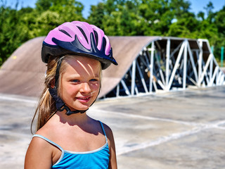 Portrait of little girl in roller skates on ride in skatepark.