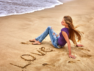 Summer girl sea.  Teenager writting love  on sand and lookong on sea.