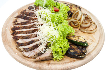 meat roasted on a grill with vegetables on a wooden plate