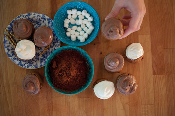 process of cooking cupcakes, muffins and  ingredients for decoration on the table. woman's hand holds one cupcake