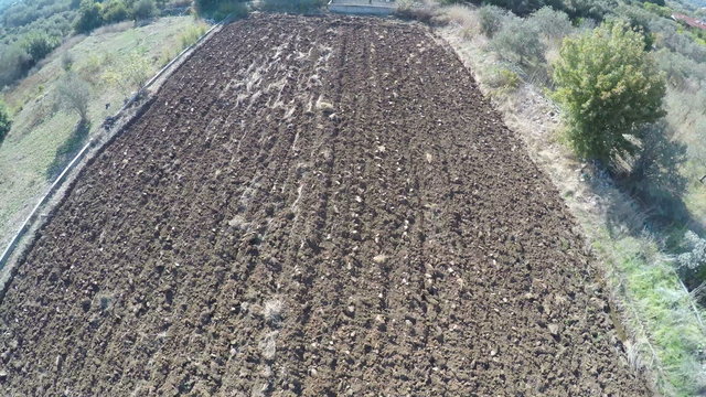Flying above a plowed field.