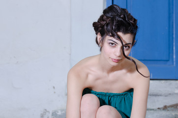 Fashion slim woman wearing green strapless short dress bending front and facing the camera