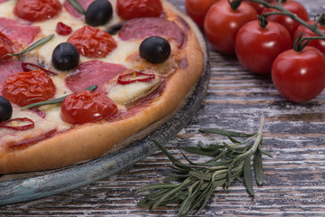 Italian pizza with mozzarella and tomatoes on wooden background