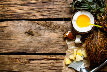 Fresh cocktail in a cup of coconut rum and pineapple on a wooden table. Free space for text.