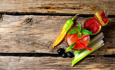 Cocktail with peppers, tomatoes, celery, vodka and other ingredients on wooden background . Free...