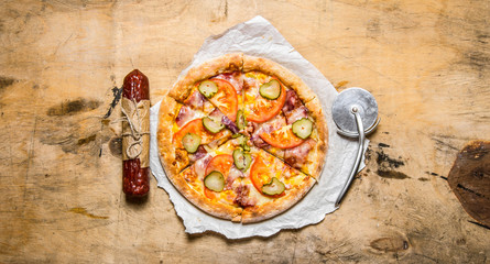 Tasty pizza with bacon and tomatoes. On wooden table.