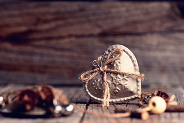 Silver heart on a wooden table with decorations. Valentines day. Love. Gift on a natural background. Candle and fire like a background