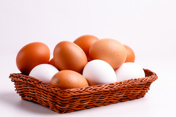 Brown and white chicken eggs lying in a wicker basket.