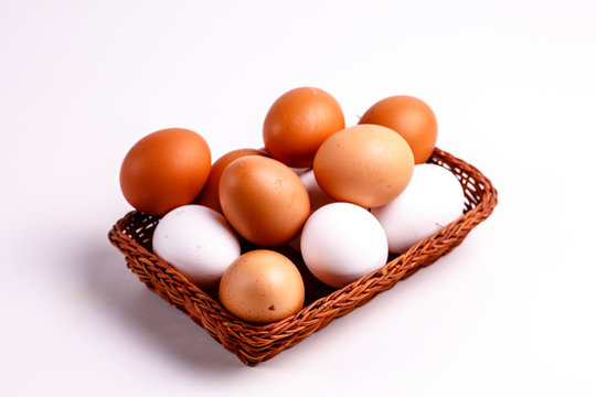 Brown and white chicken eggs lying in a wicker basket.