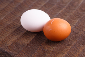 ..Brown and white chicken eggs lying on a dark wavy Board.