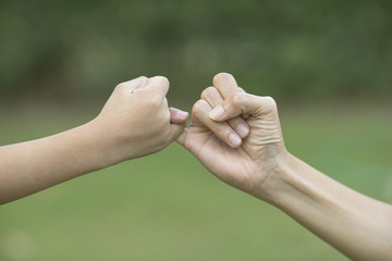 A mother and her child hooking their fingers to make a promise