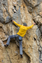 Young male climber hanging by a cliff.