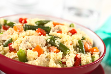 Couscous dish with chicken, green bean, carrot and red bell pepper served in a red bowl (Selective Focus, Focus one third into the dish)