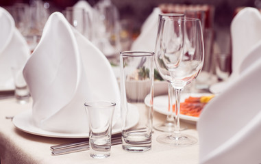 Сервировка стола, белые салфетки на тарелке и бокалы 