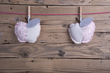 Decorative cushions shaped apple hanging on clothesline on old wooden background