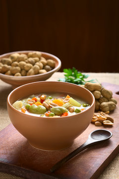 Traditional Bolivian Sopa de Mani (peanut soup) made of meat, pasta, vegetables (pea, carrot, potato, broad bean, pepper, corn), ground peanut, photographed with natural light (Selective Focus)