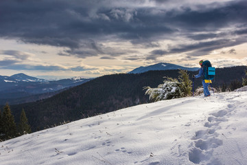 Young girl tourist with backpack hiking in the winter mountains. Concept of freedom.