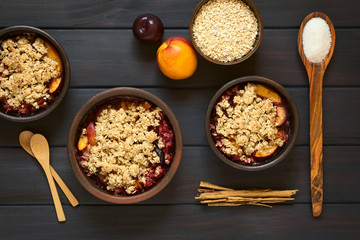 Baked plum and nectarine crumble or crisp, photographed on dark wood with natural light