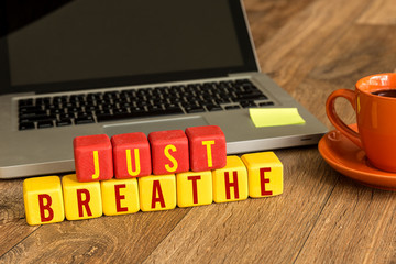 Just Breathe written on a wooden cube in a office desk