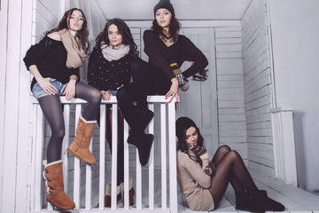 Four stylish models posing sitting on the fence