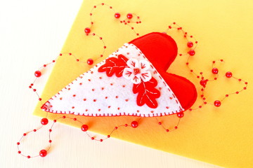 Handmade felt heart - symbol of Valentines Day, felt white and red heart toy on yellow background 