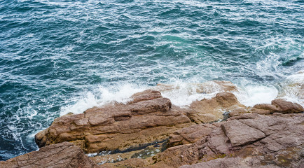 Splashing ocean waves crashing against bare rocks