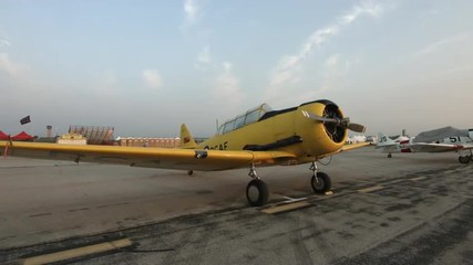 Pan across to a wide angle view of a T-6 Harvard (also known as a Texan) training aircraft, parked at airfield.  Recorded in 4K, ultra high definition.