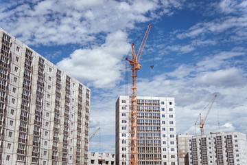 Fototapeta na wymiar High-rise houses and construction cranes