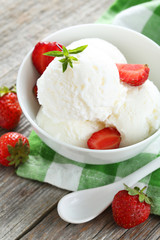 Ice cream in bowl with strawberries on grey wooden background