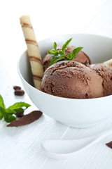 Sweet chocolate ice cream in bowl on grey wooden background