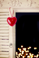 Red wooden heart hanging on the old rustic window