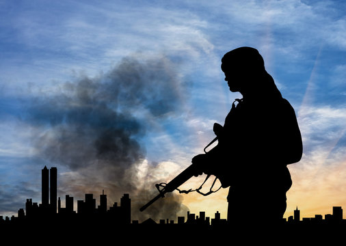 Silhouette of armed man against city in smoke