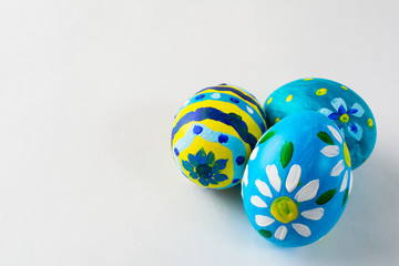 Blue hand-painted Easter eggs with floral design on a white background. Easter background. Easter symbol. Copy space