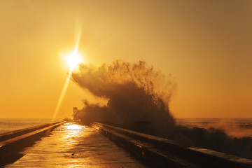 Wave splash at sunset near lighthouse