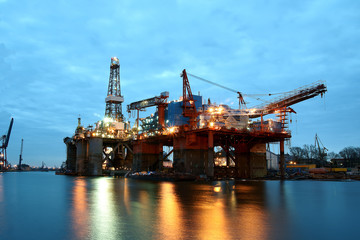 Fototapeta na wymiar Evening view of the two drilling platforms standing in the shipbuilding channel during renovation