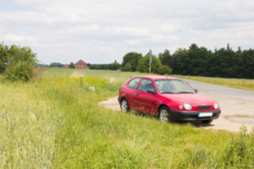Fototapeta na wymiar Blurred photo of car standing next to the meadow