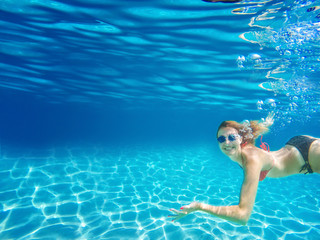 Female snorkeling underwater and looking at camera. Deep blue sea. Clear water.