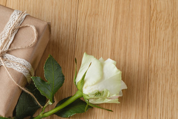 gift box and white rose on wooden background