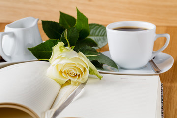 rose and empty notebook page on wood background