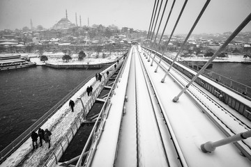 People walking on the Golden Horn Metro Bridge on a snowy day, 2016.