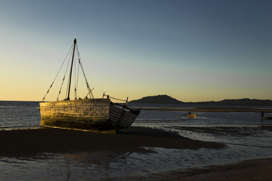 Old white vessel stranded on low tide Madagascar sunset