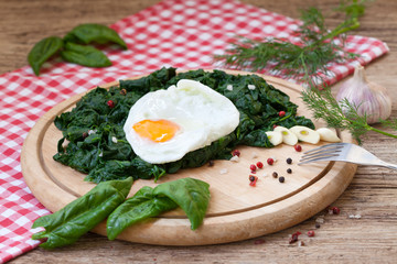 Baked egg with spinach on rustic background