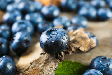 Tasty ripe blueberries with green leaves on wooden table close up