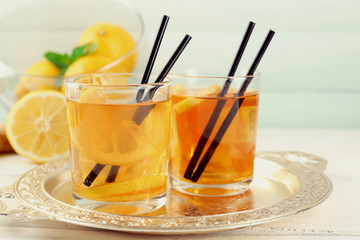 Iced tea with lemon on light wooden background